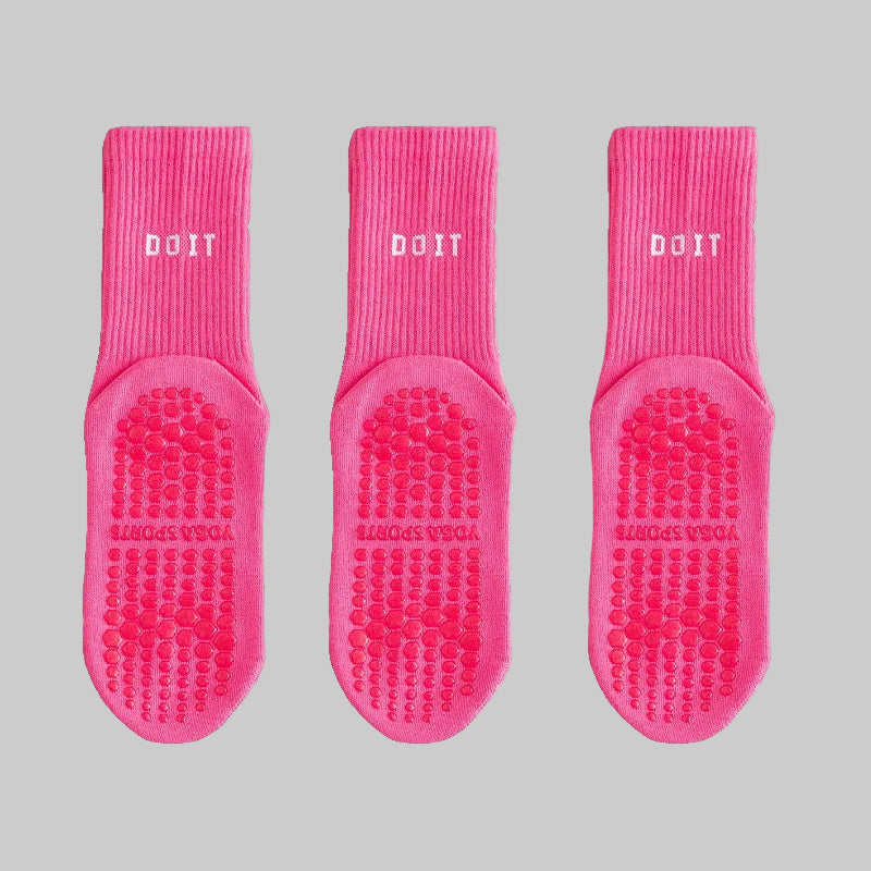Three pairs of pink socks with textured soles on a white background