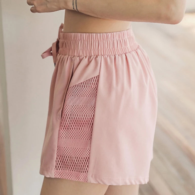 Pink shorts with mesh panel on a neutral background