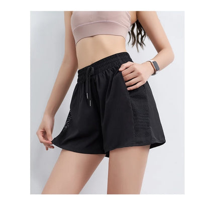 Person wearing black athletic shorts on a plain background