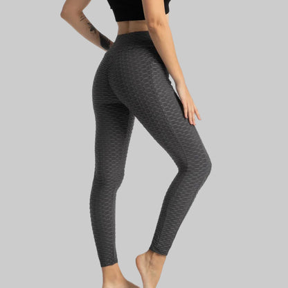 Person wearing dark gray patterned leggings on a white background