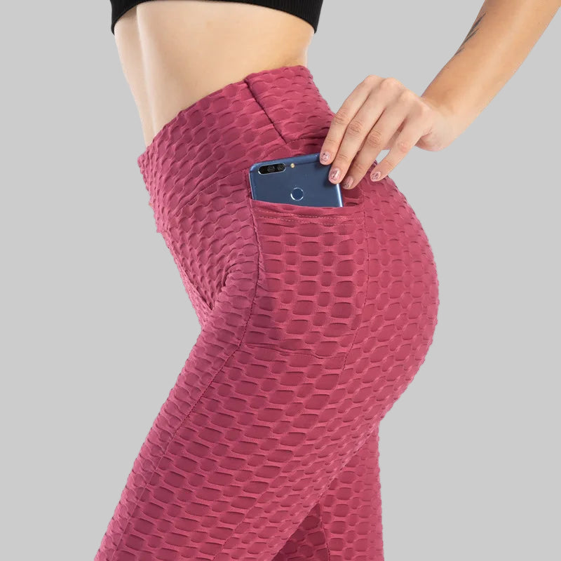 Person wearing pink leggings with a phone in the pocket on a white background