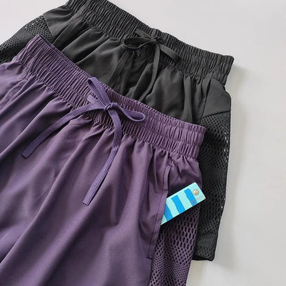 Two pairs of shorts, one purple and one black, on a light gray background.
