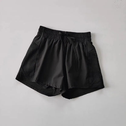 Black shorts with mesh panels on a light gray background