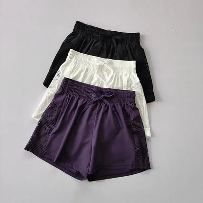 Three pairs of shorts in black, white, and purple on a gray background