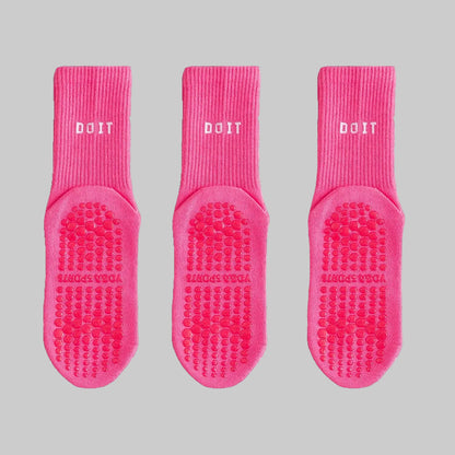 Three pairs of pink socks with textured soles on a white background