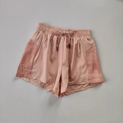 Pink athletic shorts with mesh panels on a gray background