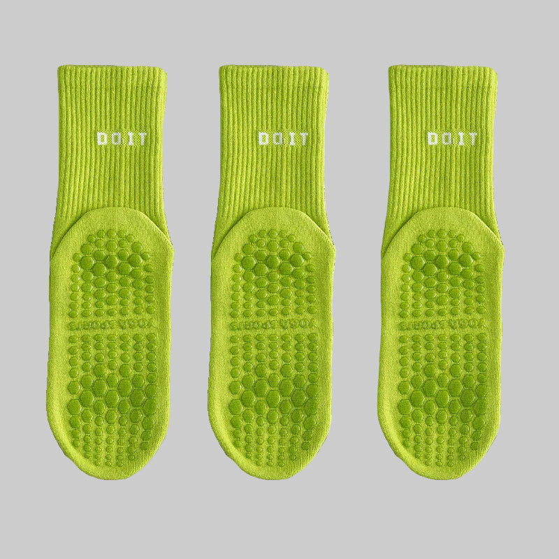Three green socks with textured soles on a white background