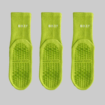 Three green socks with textured soles on a white background