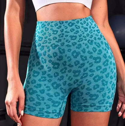 Teal leopard print shorts worn by a person against a dark background